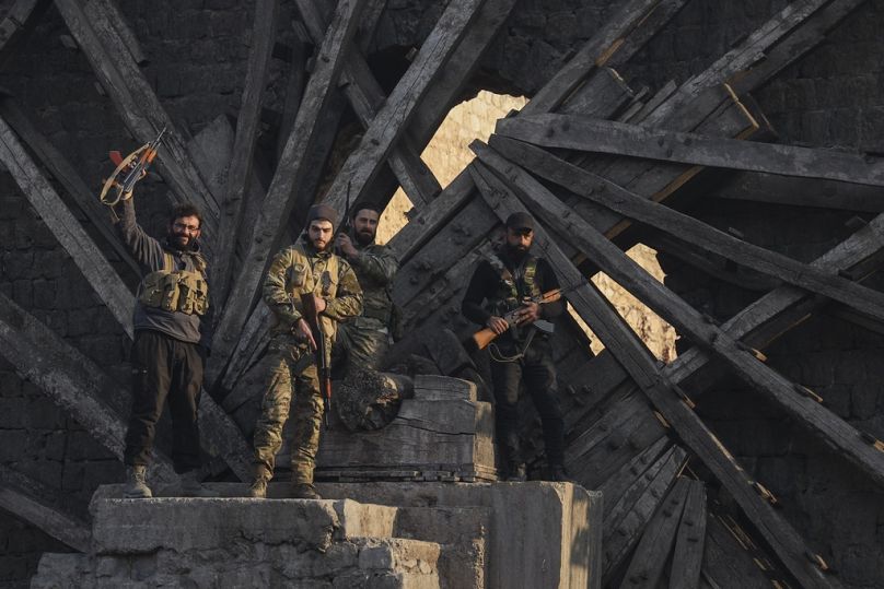 Fighters celebrate in the aftermath of the opposition's takeover of the city in downtown Hama, 6 December 2024