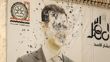 An image of Syrian President Bashar Assad, riddled with bullets, is seen on the provincial government office in Hama, 6 December, 2024