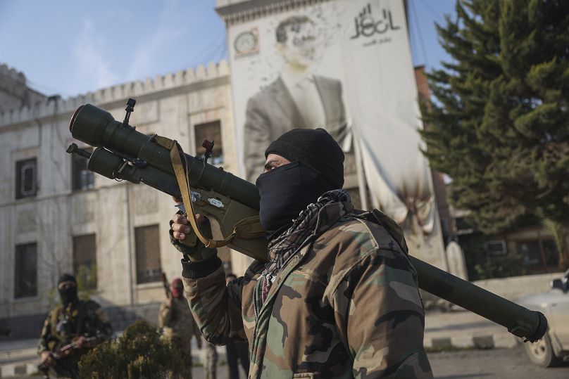 A Syrian opposition fighter holds a rocket launcher in front of the provincial government office in Hama, 6 December, 2024