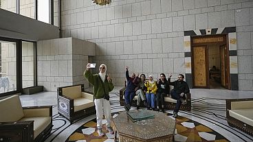 A group of people take a family photo in a room of Syrian President Bashar al-Assad's presidential palace in Damascus, Syria, 8.12.2024