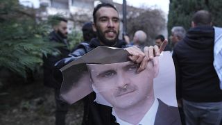 Un uomo strappa una foto del presidente siriano Bashar al-Assad davanti all'ambasciata siriana a Belgrado, 8 dicembre 2024