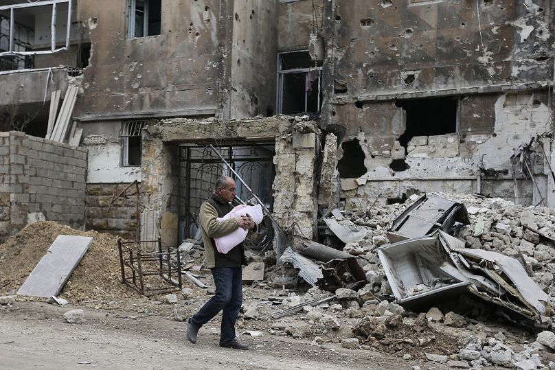 Férfi kisgyerekkel a Szalaheddin negyedben Aleppóban, 2024 januárjában 