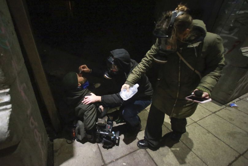 Demonstrators help a journalist who was injured by tear gas during a rally outside the parliament's building, Dec. 1, 2024