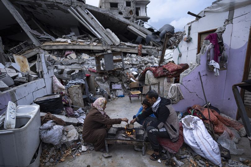 فلسطينيون يتناولون الطعام خارج منزلهم، الذي دمرته غارة جوية إسرائيلية، في رفح، قطاع غزة، في 18 مارس، 2024. 