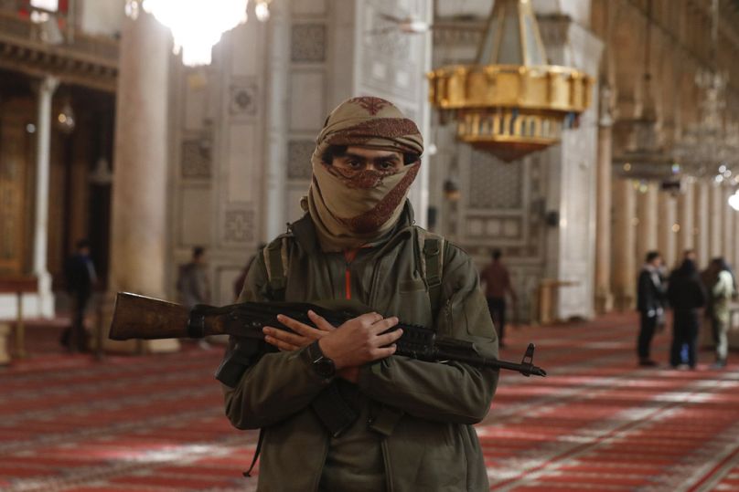 An opposition fighter poses for a photograph inside the 7th century Umayyad Mosque in Damascus, Syria, Wednesday, Dec. 11, 2024