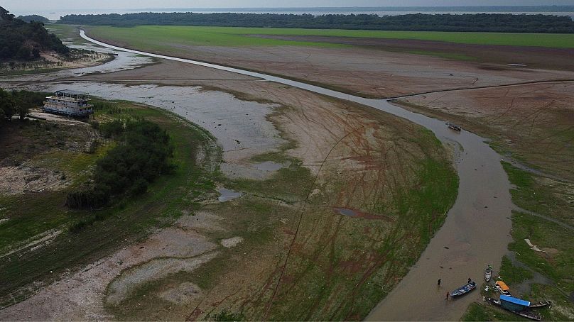 Pescadores empurram um barco no Lago do Aleixo durante uma seca em Manaus, estado do Amazonas, Brasil, setembro de 2024