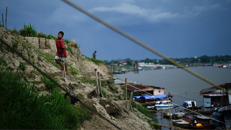 Um rapaz sobe uma colina perto de um rio Amazonas baixo devido à seca, em Leticia, Colômbia, outubro de 2024