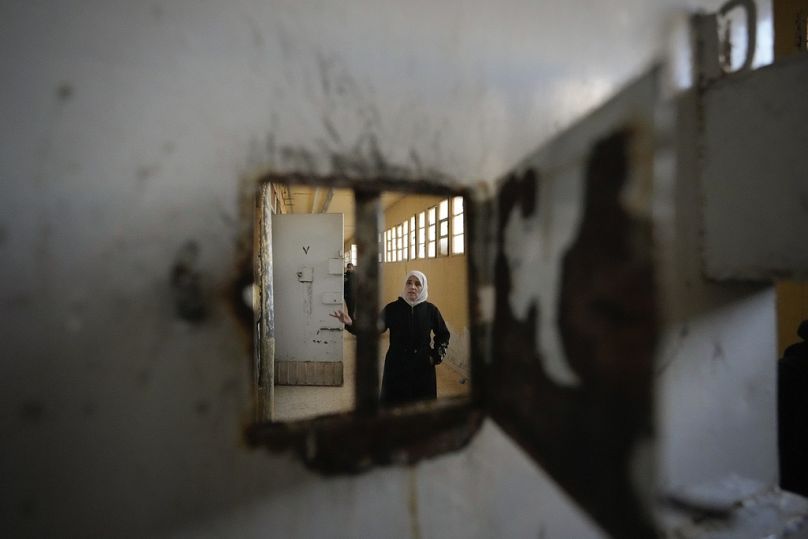 امرأة تتفحص الزنازين في سجن صيدنايا، شمال دمشق، سوريا، يوم الاثنين 9 ديسمبر/كانون الأول 2024.