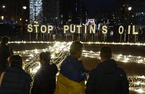 Persone in piedi intorno a un gigantesco cartello di pace affisso dai manifestanti prima di un vertice Ue e Nato a Bruxelles, 22 marzo 2022