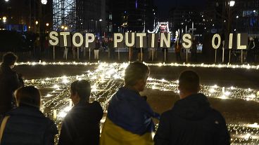 People stand around a giant peace sign put up by demonstrators ahead of an EU and NATO summit in Brussels, Tuesday, March 22, 2022.