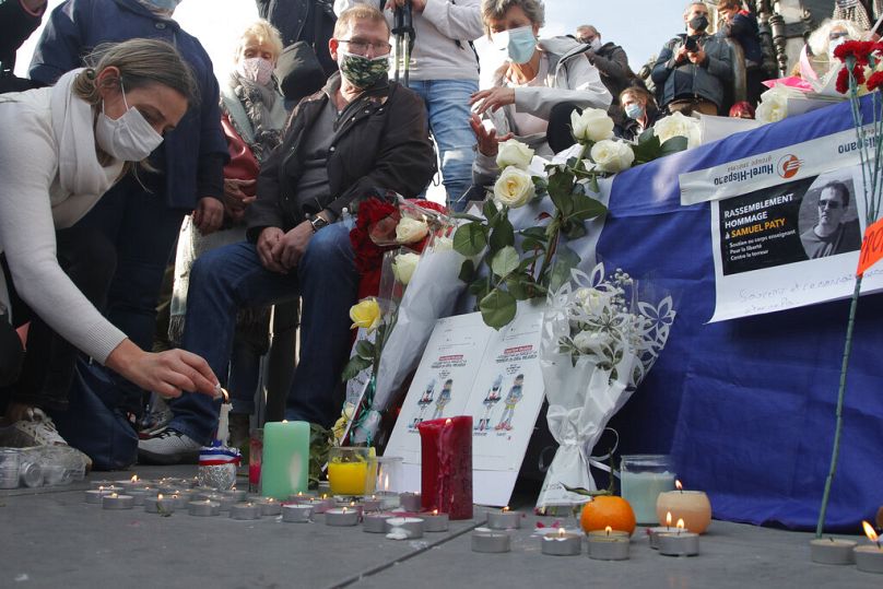 امرأة تضيء شمعة في ساحة الجمهورية خلال مظاهرة الأحد 18 أكتوبر 2020 في باريس.