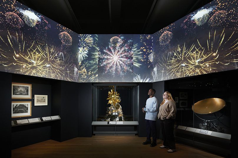 Des visiteurs regardent un rendu numérique des feux d'artifice à Versailles.