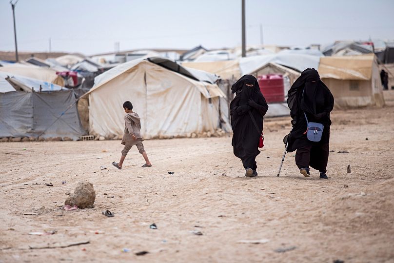 نساء يمشين في مخيم الهول الذي يضم حوالي 60,000 لاجئ في محافظة الحسكة بسوريا، في 1 مايو/أيار 2021