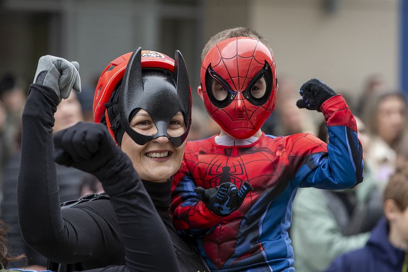 A child dressed as Spiderman poses with a Kosovo alpinist disguised as superheroes delivering Christmas gifts in Pristina, 13 December, 2024