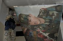 A Syrian rebel removes a poster of former President Bashar al-Assad in Damascus, 14 December, 2024