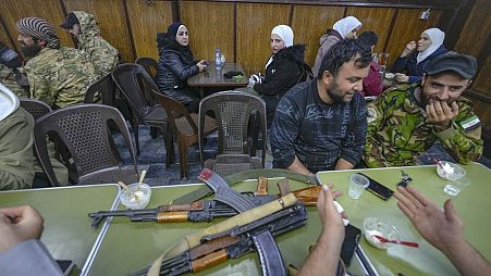 DATEI - Oppositionskämpfer sitzen in einem Restaurant auf dem Al-Hamidiyeh-Markt in der alten Stadtmauer von Damaskus, Syrien, Dienstag, 10. Dezember 2024. (AP Photo/Hussein Malla)