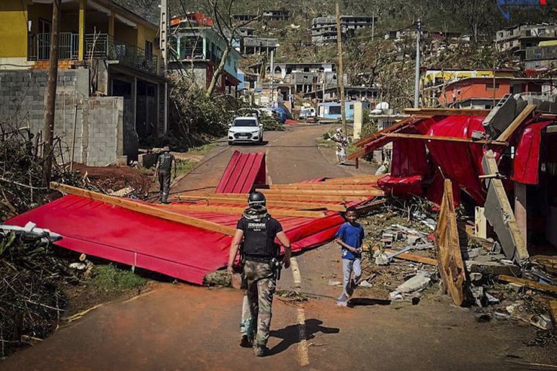 This photo provided on Monday Dec.16, 2024 by the Gendarmerie Nationale, shows a French Gendarme walking in among debris in Mayotte.