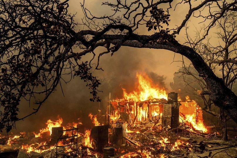 As chamas consomem uma estrutura em Bessie Lane enquanto o incêndio Thompson arde em Oroville, Califórnia. 