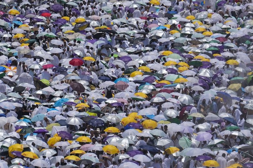 Peregrinos usam chapéus-de-chuva para se protegerem do sol, enquanto se reúnem à porta da mesquita de Nimrah para oferecer as orações do meio-dia em Arafat, durante a Hajj 