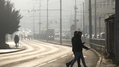 Люди переходят улицу, окутанную смогом. Сараево, Босния и Герцеговина, в декабре 2024 года.