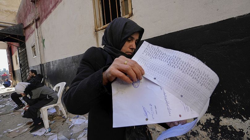 A woman looks through a list of names in a document found on the floor at the infamous Saydnaya military prison, just north of Damascus, Syria, Monday, Dec. 9, 2024.