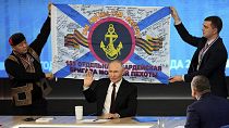 Men hold a replica of the banner of the 155th Marine Brigade of the Pacific Fleet, during Russian President Vladimir Putin's annual news conference in Moscow, 19 December 2024