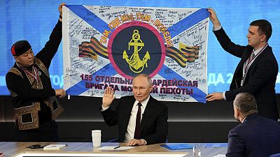 Men hold a replica of the banner of the 155th Marine Brigade of the Pacific Fleet, during Russian President Vladimir Putin's annual news conference in Moscow, 19 December 2024