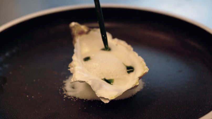 Um prato de teste de conceito feito com fungos servido numa concha de ostra com espuma e molho