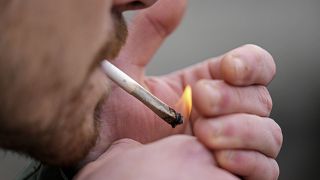 A man smokes cannabis in Cologne, Germany, at a public consumption event at the start of a new law in April 2024. 