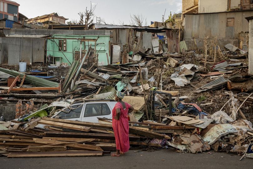 Una donna osserva una casa distrutta a Mamoudzou, Mayotte, 19 dicembre 2024