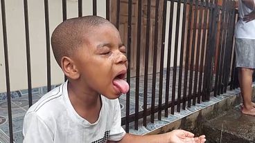 Mayotte, Children, eyes closed, try to drink rainwater by sticking out their tongues.