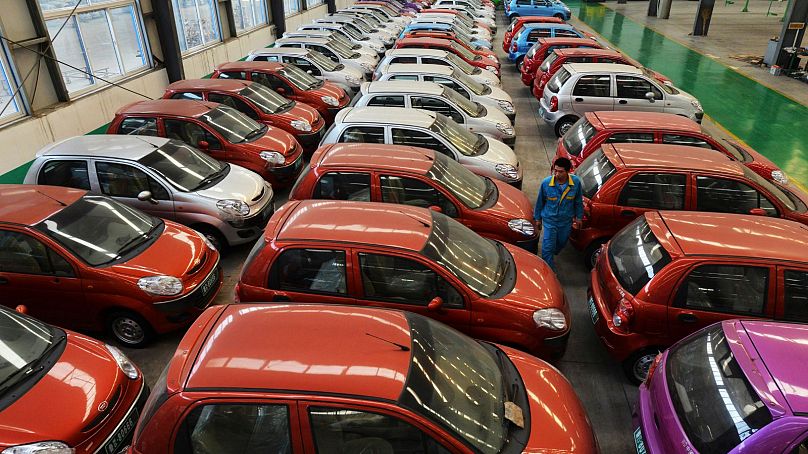 A worker walks among electric cars in a factory in Zouping county in eastern China's Shandong province, 2013.