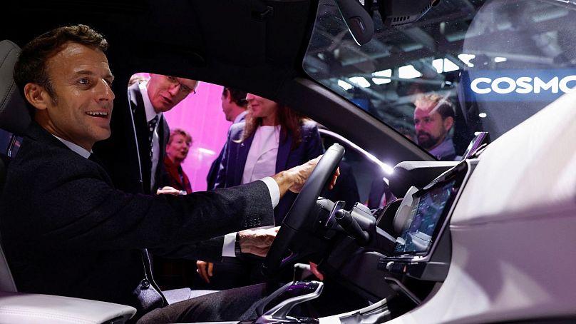 French President Emmanuel Macron sits inside a Peugeot EV at the Paris Car Show, October 2022. 