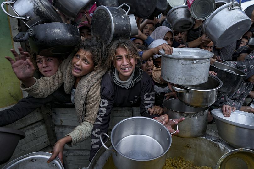 نساء وفتيات فلسطينيات يكافحن للوصول إلى الطعام في مركز توزيع في خان يونس، قطاع غزة، الجمعة، 20 ديسمبر 2024