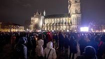 Le persone assistono a una cerimonia commemorativa fuori dalla cattedrale vicino al mercatino di Natale, dove un'auto ha investito la folla venerdì sera, 21 dicembre 2024.