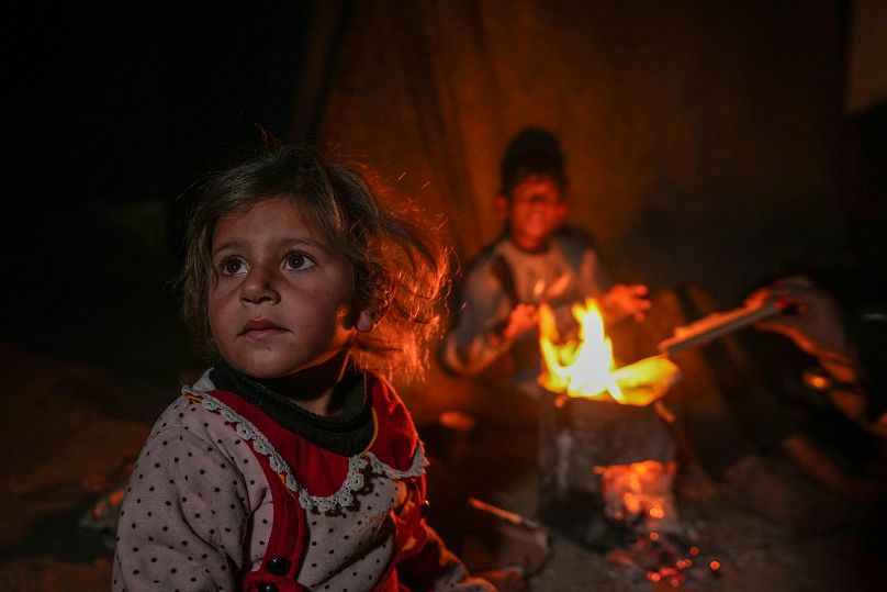 أحفاد رضا أبو زرادة يجلسون بجوار النار في مخيم على البحر في خان يونس، قطاع غزة، الخميس، 19 ديسمبر 2024