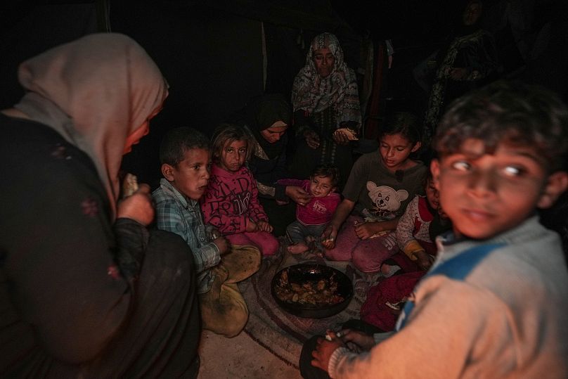 أماني أبو زرادة، الرابعة من اليسار، تطعم أحد أطفالها  خارج خيمتهم في مخيم في خان يونس، قطاع غزة، الخميس 19 ديسمبر 2024