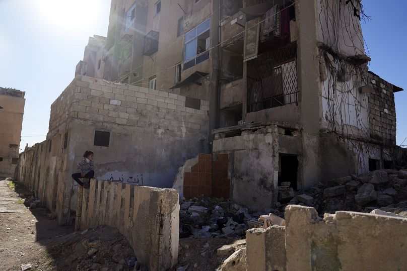 Une fillette syrienne joue à côté d'un immeuble résidentiel détruit dans le quartier de Hanano dans la ville d'Alep, en Syrie, le samedi 14 décembre 2024.