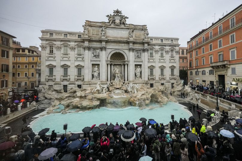 People admire the 18th century Trevi Fountain, one of Rome's most iconic landmarks in Rome, Sunday, Dec. 22, 2024.