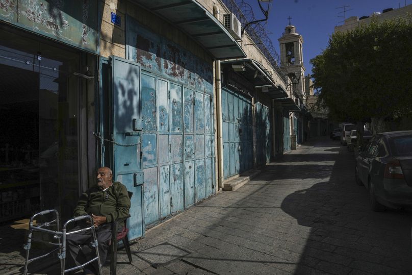 رجل يستريح بجوار المتاجر الفارغة بالقرب من كنيسة المهد قبل عيد الميلاد في مدينة بيت لحم 17 كانون الأول ديسمبر 2024