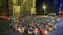 Flowers, candles, wreaths and stuffed animals lie in front of St. John's Church, Monday, Dec. 23, 2024, in Madgeburg, Germany, after a car drove into a Christmas market