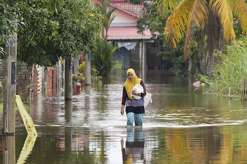 Une femme avance dans les eaux de crue à Tumpat, dans la banlieue de Kota Bahru, dans l'État de Kelantan, sur la côte est de la Malaisie, le mardi 3 décembre 2024.