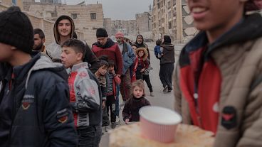 Syrians wait to receive food in Aleppo