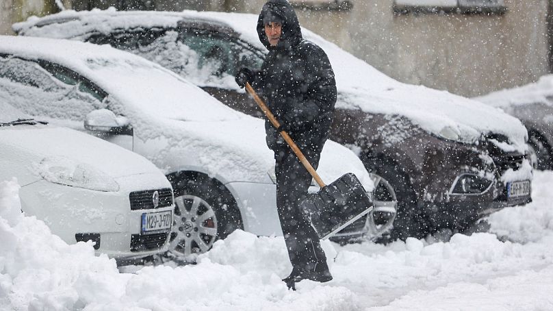 Um homem retira neve da rua durante uma forte queda de neve em Bihac, na Bósnia.