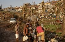 People line up to collect water in Barakani, Mayotte, home Saturday, Dec. 21, 2024.