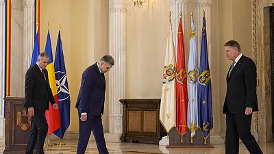 Romanian Prime Minister Marcel Ciolacu, and Romanian President Klaus Iohannis look for their designate places for a family picture after a swearing in ceremony