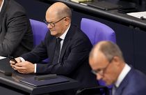 Outgoing Chancellor Olaf Scholz checks his phone in the German parliament.