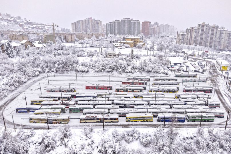 An aerial view of parked trolley buses during heavy snowfall in Sarajevo, Bosnia, Tuesday, Dec. 24, 2024