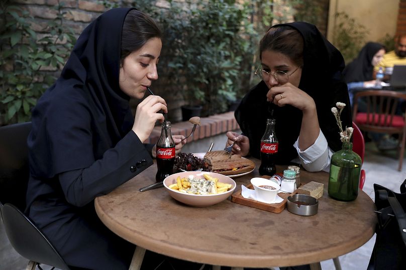 إيرانيتان تشربان الكوكا كولا في مقهى بوسط طهران، إيران، الأربعاء، 10 يوليو 2019