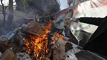 A banner of ousted Bashar al-Assad is placed on a fire as rebel forces destroys drugs and alcohol, found at a complex building, in Damascus, Syria, Wednesday, Dec. 25, 2024